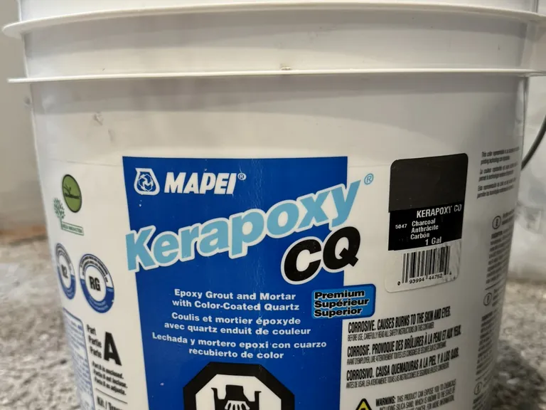 Epoxy grout on a porcelain floor: a two-part mix (left), worked in small sections with the tile edges taped (right).