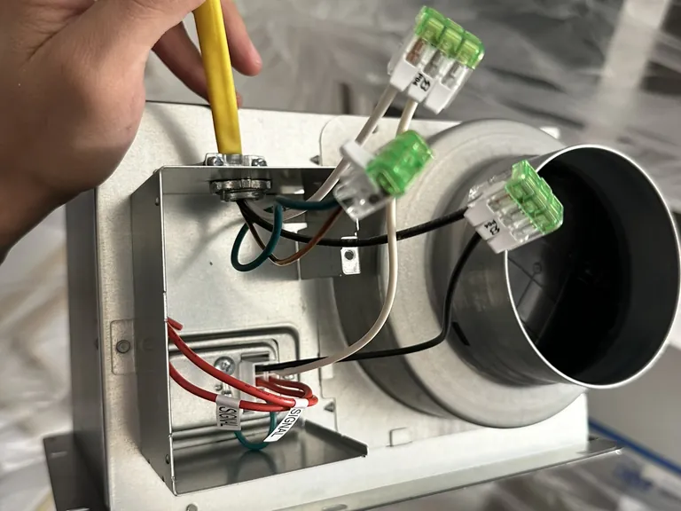A new fan housing wired before it goes into the ceiling (left), and the finished fan grille next to a heating register (right).
