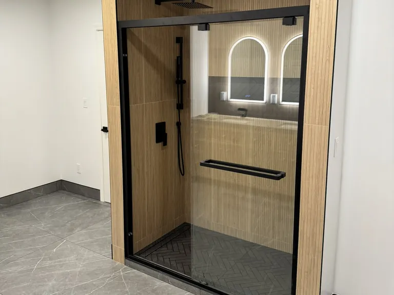 A walk-in shower with a low curb and a sliding glass door.
