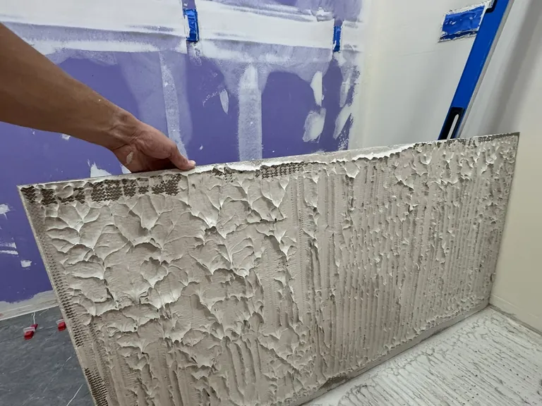 Large-format porcelain: mortar spread on the back of each tile for full contact (left), and leveling clips at every joint so the edges sit flush (right).