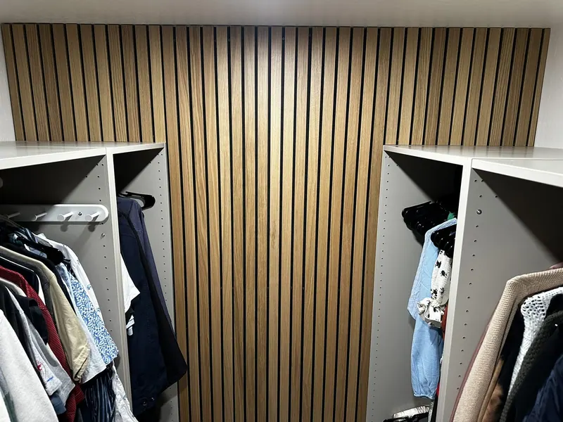 Walk-in closet with a wood slat accent wall and white shelving