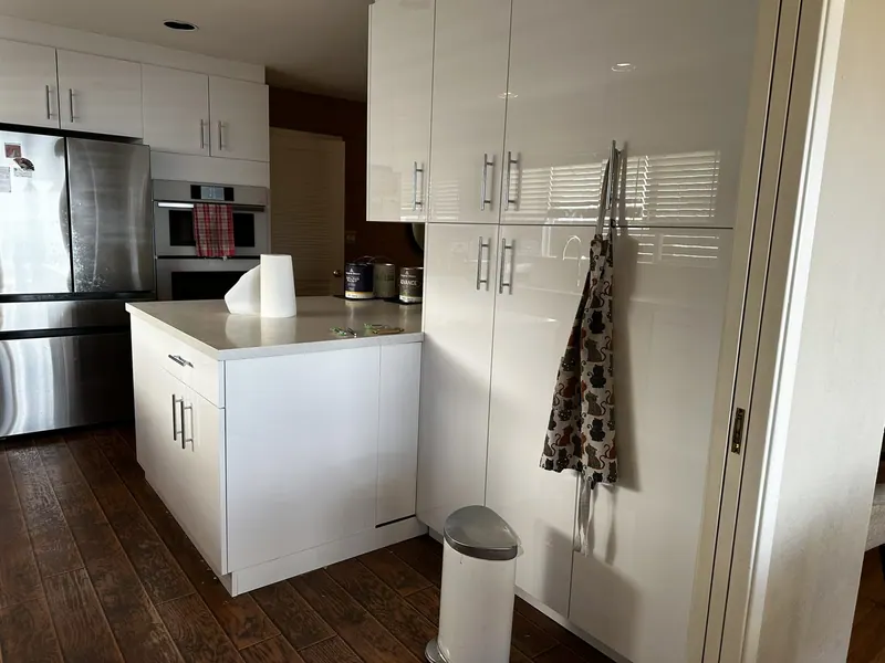 White high-gloss kitchen cabinets with island and dark wood floor