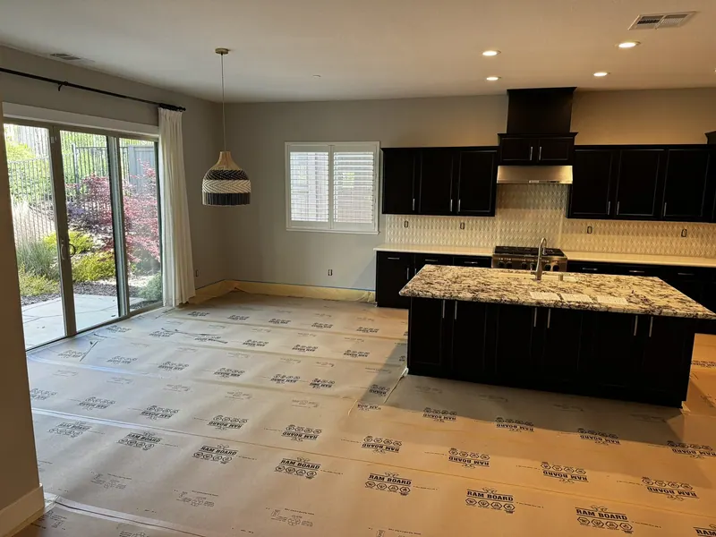 Before: White shaker kitchen with a large island, black pendant lights and stainless range hood