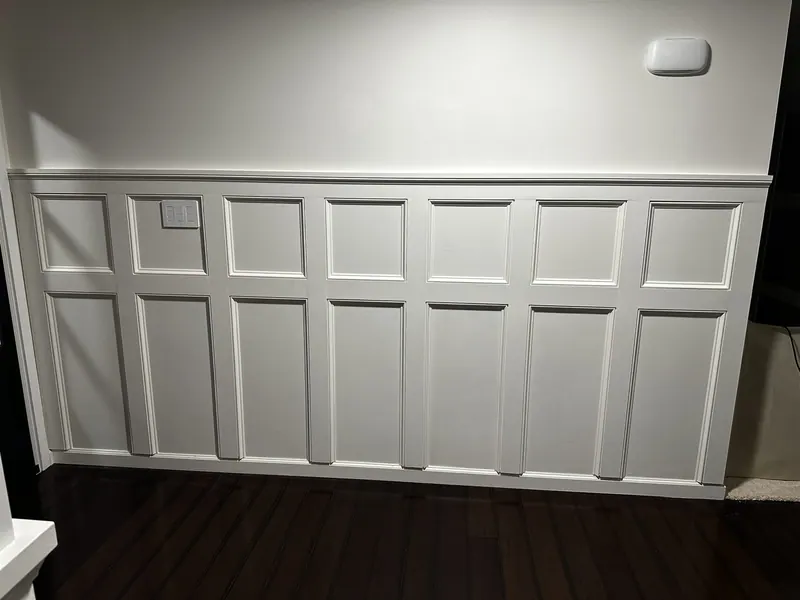 White board-and-batten wainscoting in a dining room with dark floors